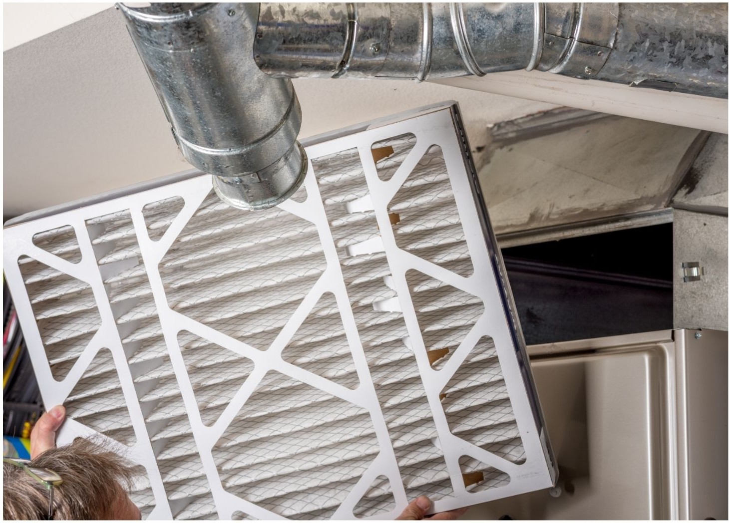 furnace inspection Branson MO - Now! Heating & Cooling technician inspecting furnace air filter beneath supply ductwork